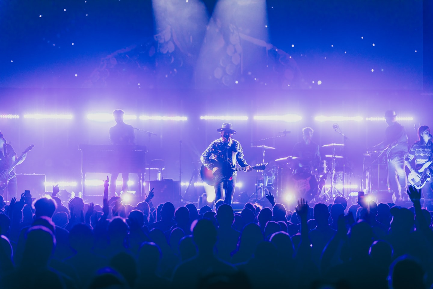 Singer-guitarist on stage under blue and purple lights.