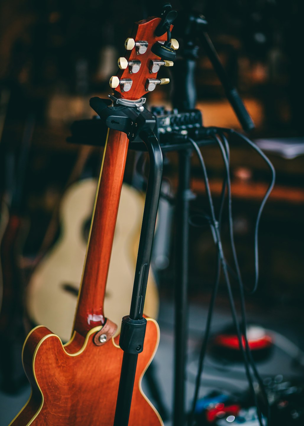 Brown electric guitar resting on a black floor stand.